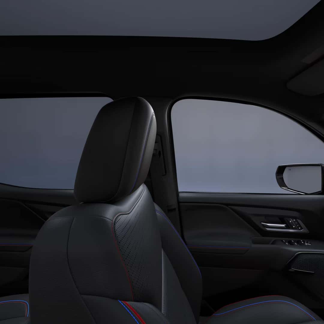 left view of the interior front seat of a chevy silverado ev with black leather interior and blue and red stiching.
