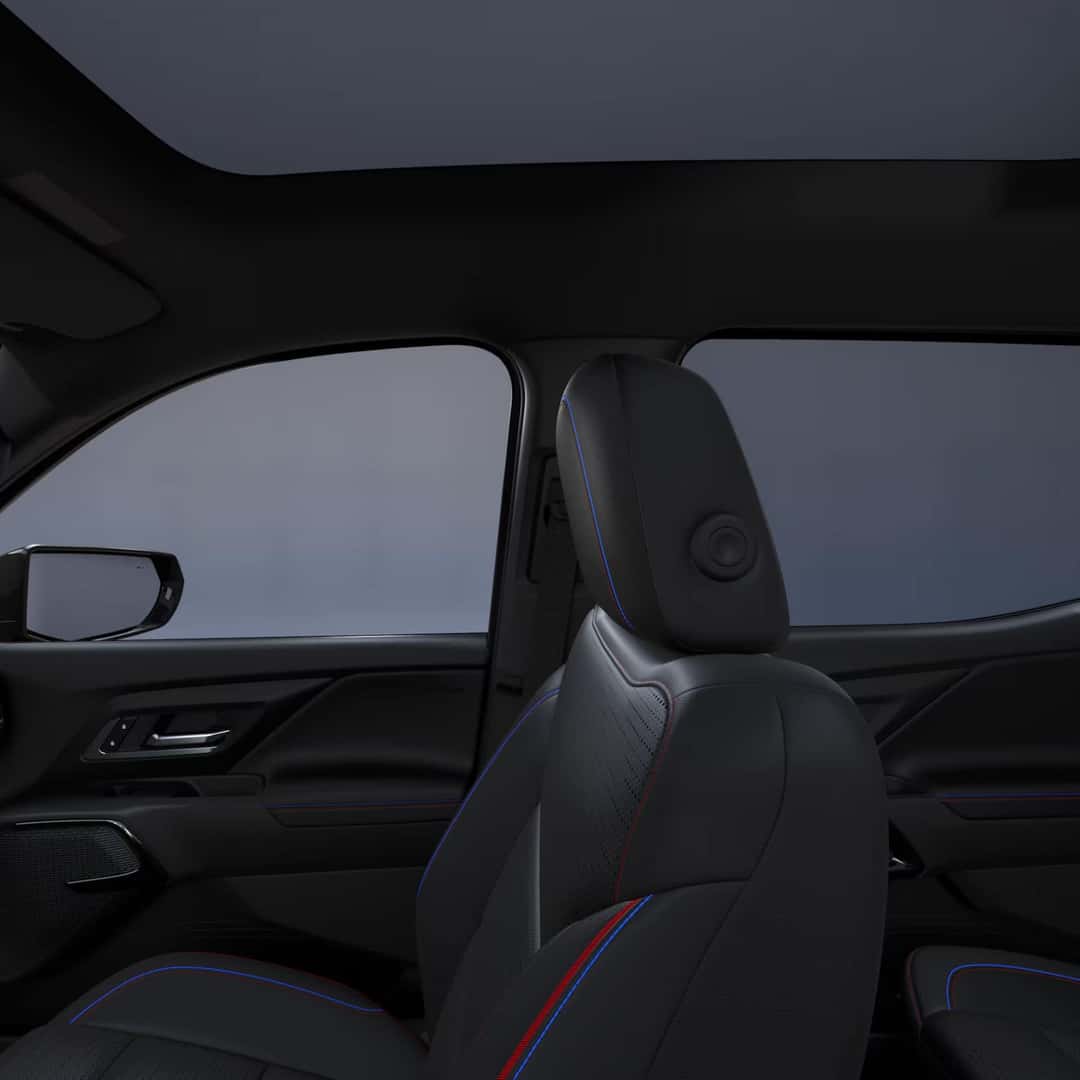 right view of the interior front seat of a chevy silverado ev with black leather interior and blue and red stiching.