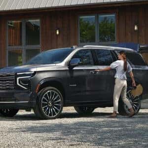 a woman getting into a tahoe suv next to a house