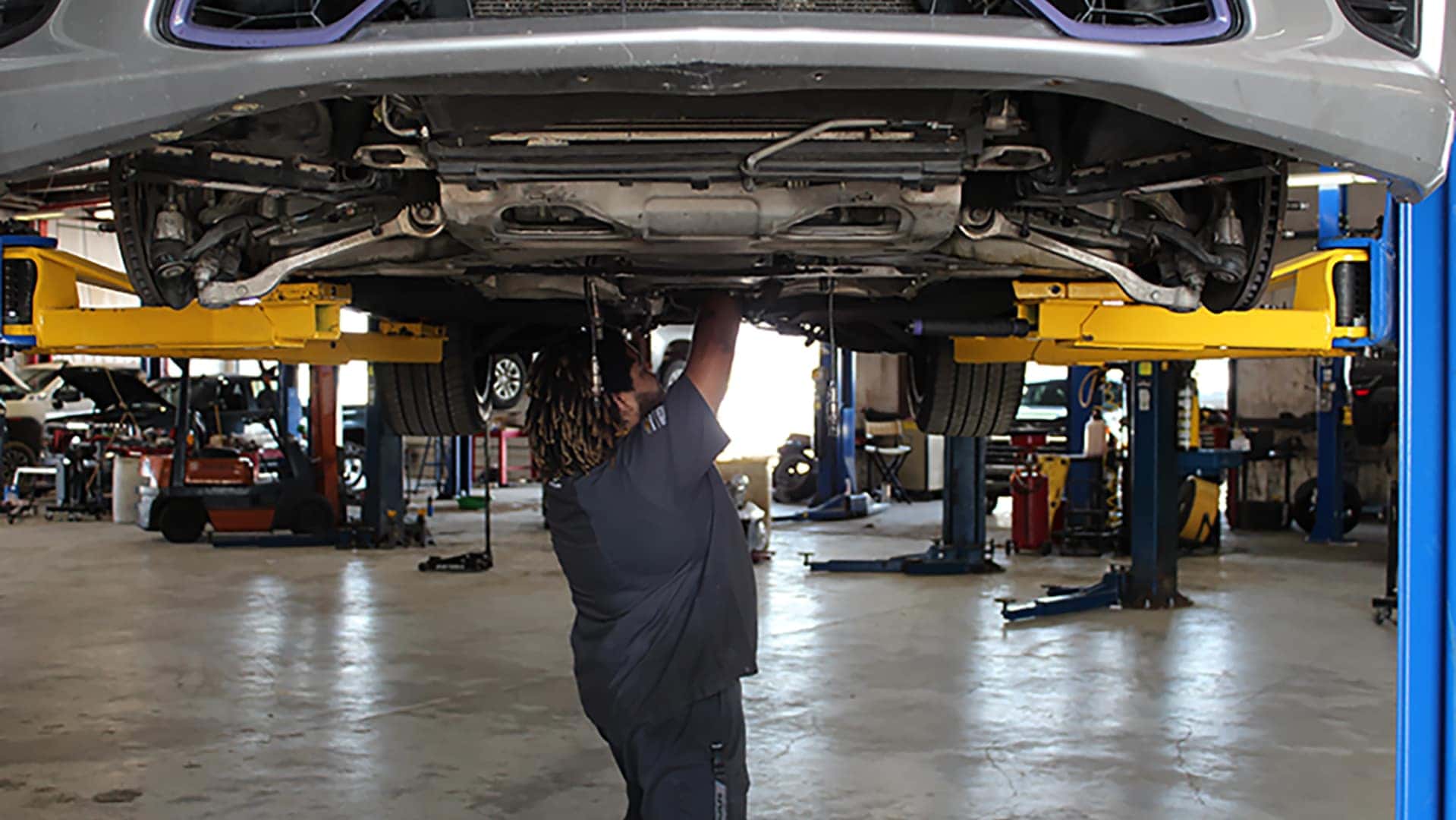 A service Mechanic looking under car