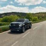Black 2026 Chevrolet Silverado 1500 RST Crew Cab driving on a two-lane highway
