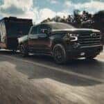 Black 2026 Chevrolet Silverado 1500 RST Crew Cab towing an enclosed travel trailer on a highway