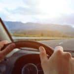 Closeup of hands on steering wheel while driving on open road