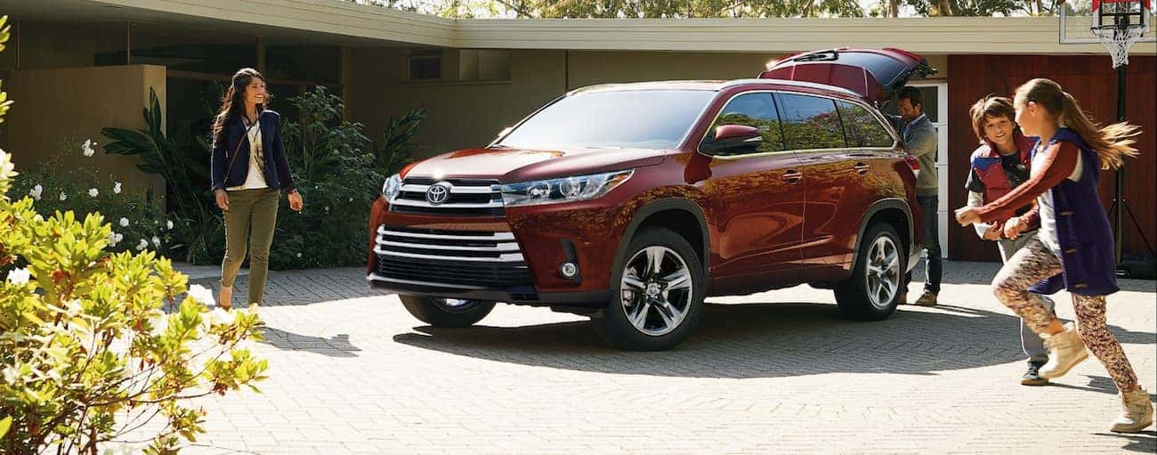 A family plays near a red 2019 Toyota Highlander parked in a driveway
