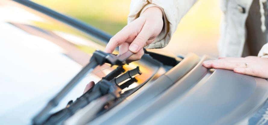 Woman touching wiper blade on car windshield