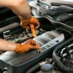 Image of a mechanic's hands working on a car engine.