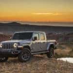 Image of a gray Jeep Gladiator truck on a hilltop at sunset.