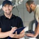 Image of a mechanic holding a clipboard and smiling at the camera.