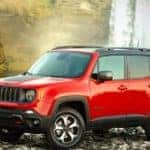 Image of a red 2019 Jeep Renegade parked in front of a waterfall.