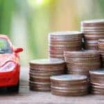 Image of a red toy car next to a stack of coins.