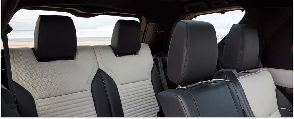 Interior rear seating with two-tone light gray and black leather trim inside a 2026 Land Rover Discovery.