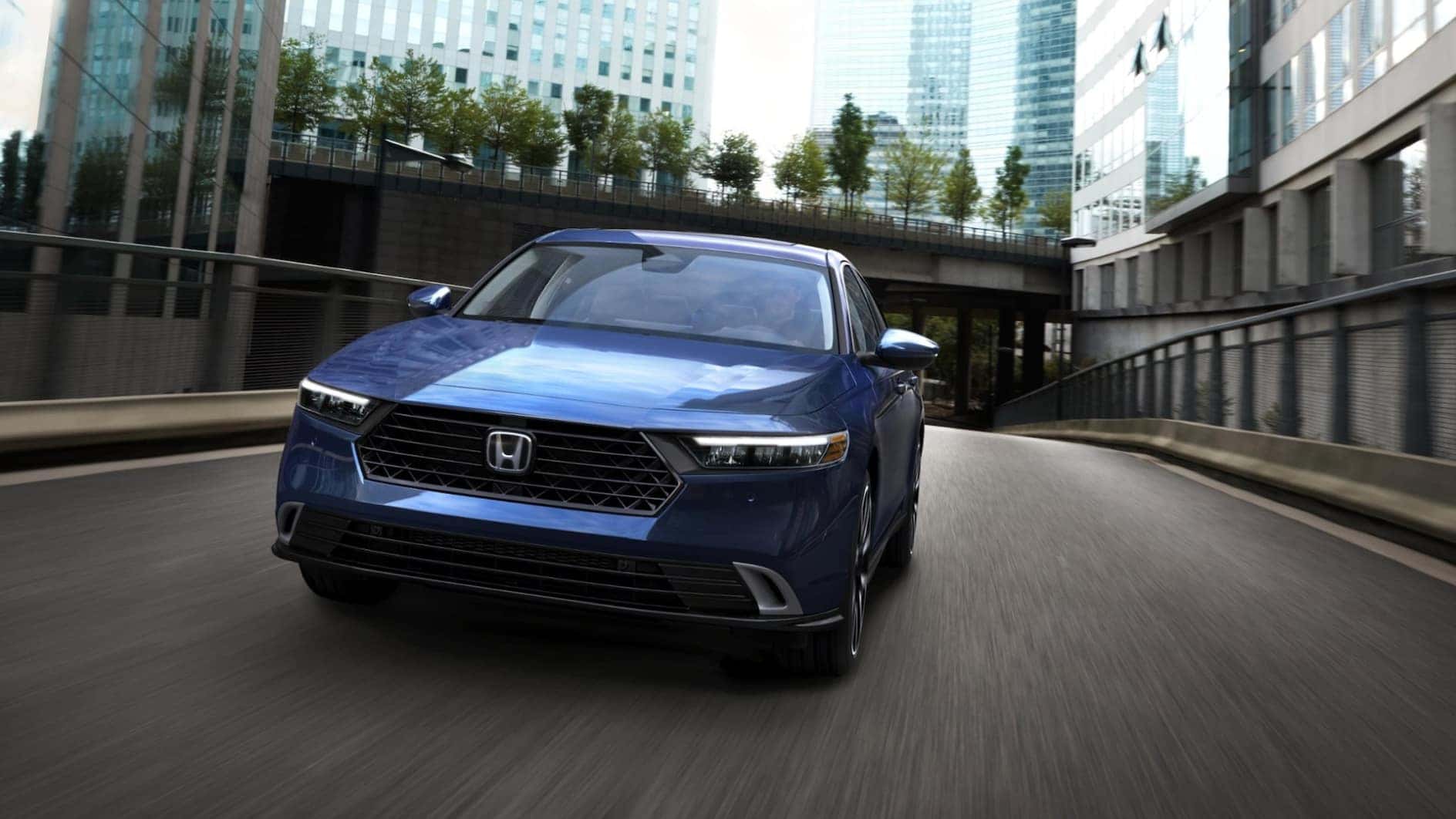 A front view of a blue Honda Accord driving through a city.