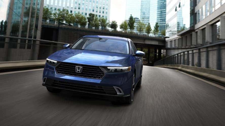 A front view of a blue Honda Accord Hybrid driving down the road.