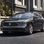 A dark grey Honda Accord parked by a curb in a city.