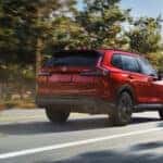 A rear view of a red Honda CR-V driving down the road.