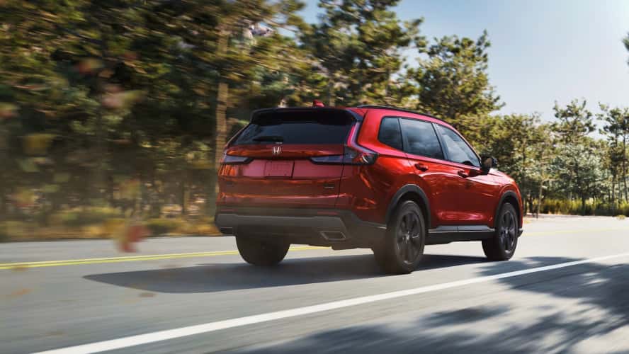 A rear view of a red Honda CR-V driving down the road.