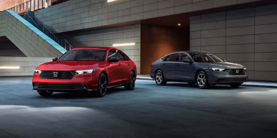 Two 2026 Honda Accord sedans, one red and one gray, parked outside a building