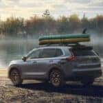 A gray 2026 Honda CR-V with boats on its roof rack, parked beside a lake