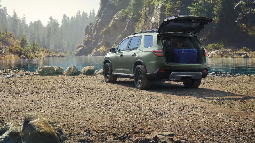 A green 2026 Honda Pilot SUV parked by the lake with its trunk open