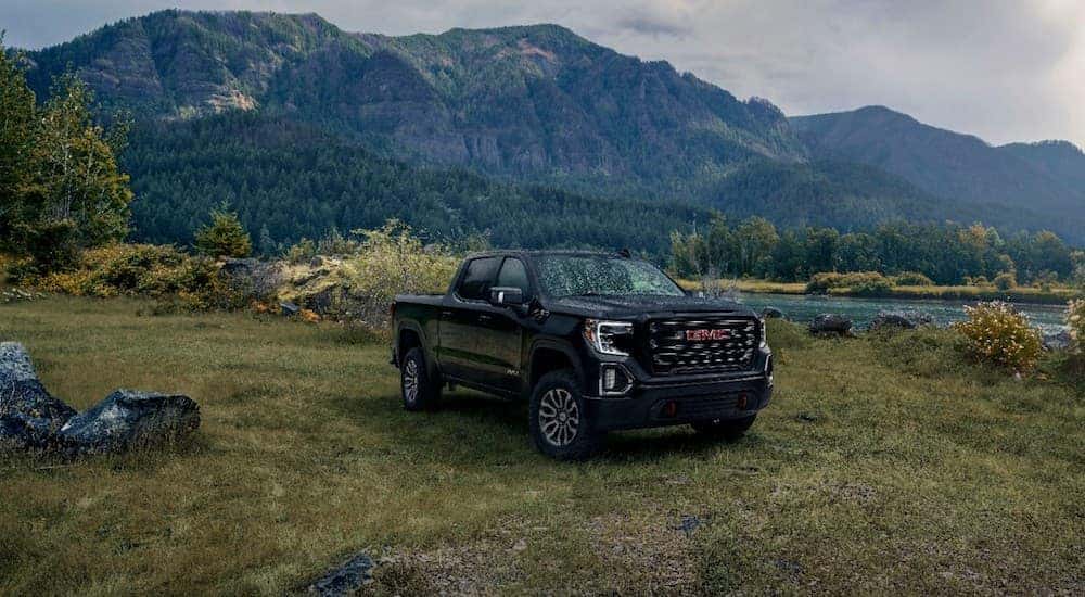 A black 2019 GMC Sierra AT4 in a field with mountains in the back