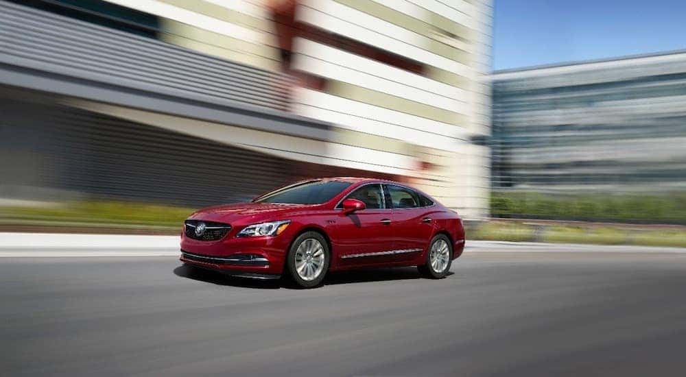 A red Buick Lacrosse is driving past buildings in Atlanta, GA. Find a model by searching 'Buick dealership near me'.