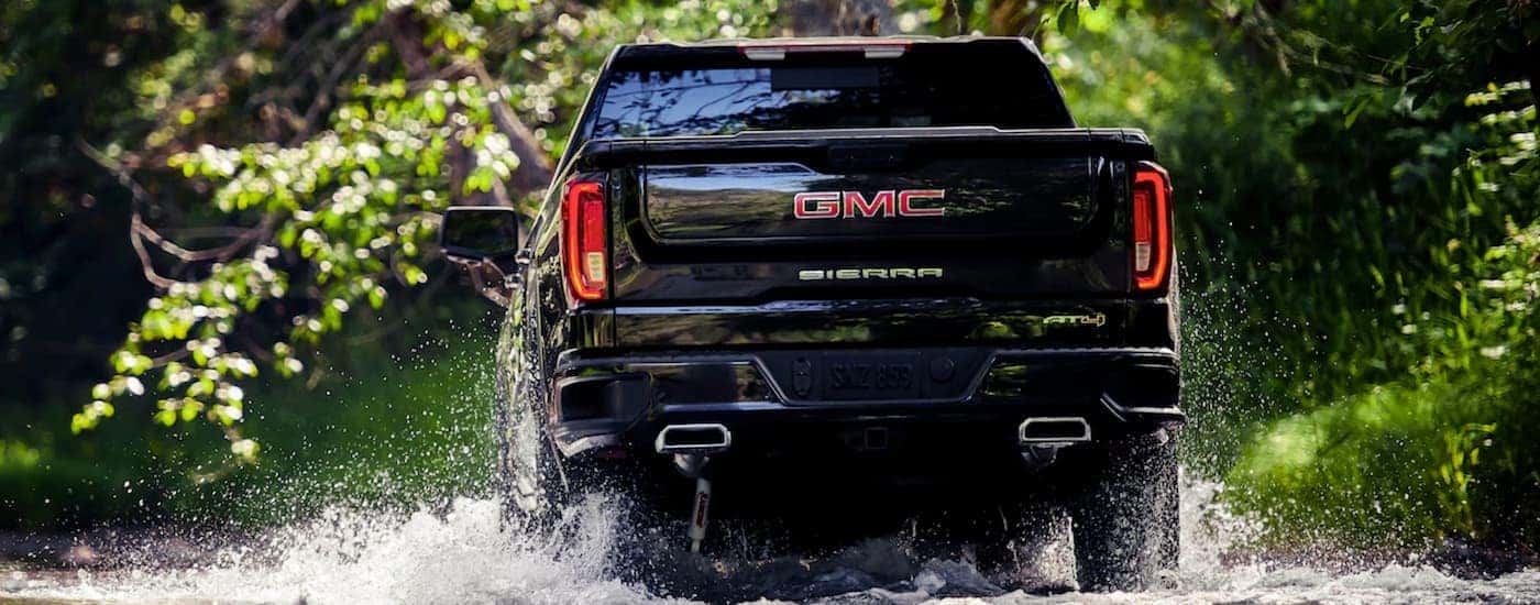 A black 2019 GMC Sierra, one of the popular trucks for sale, is driving through water in the woods outside Atlanta, GA.