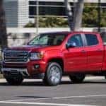 A red 2017 GMC Canyon, popular among used trucks, is driving through an intersection.