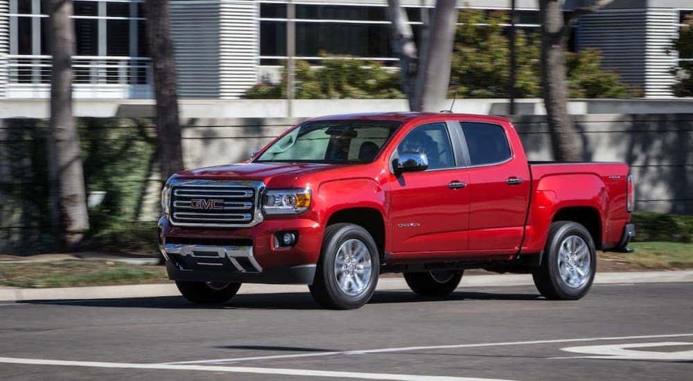 A red 2017 GMC Canyon, popular among used trucks, is driving through an intersection.