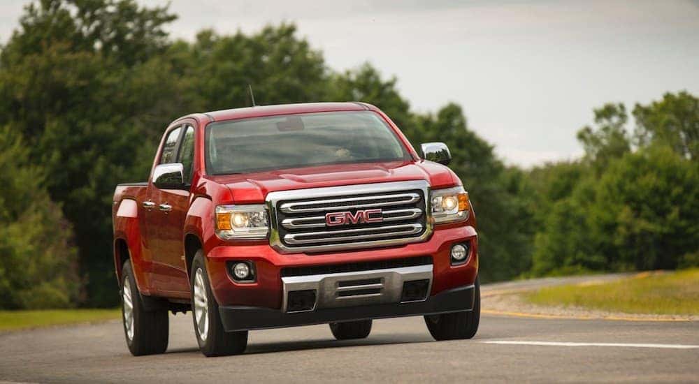 A red 2016 GMC Canyon, which is popular among used trucks for sale, is driving on a highway outside Atlanta, GA