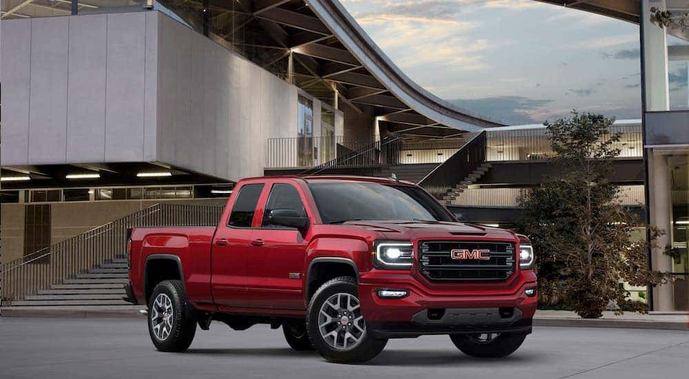 A red 2018 GMC Sierra, popular among used trucks for sale, is parked in front of a building near Atlanta, GA.