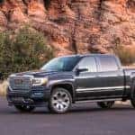 A black 2018 GMC 1500 is parked with mountains behind it.