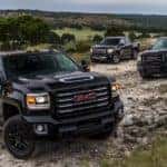 Three black 2017 GMC Sierra 2500HDs are on a rocky road.