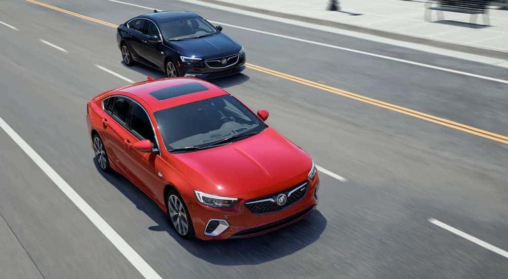 A red and a black 2019 Buick Regal GS are driving on a multi-lane highway.