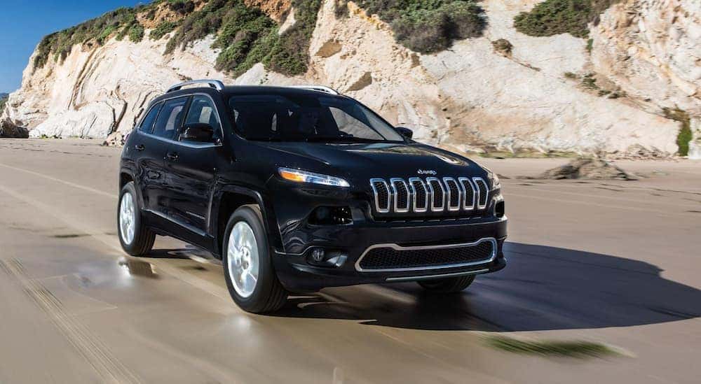 A 2018 Jeep Cherokee is driving on the beach.
