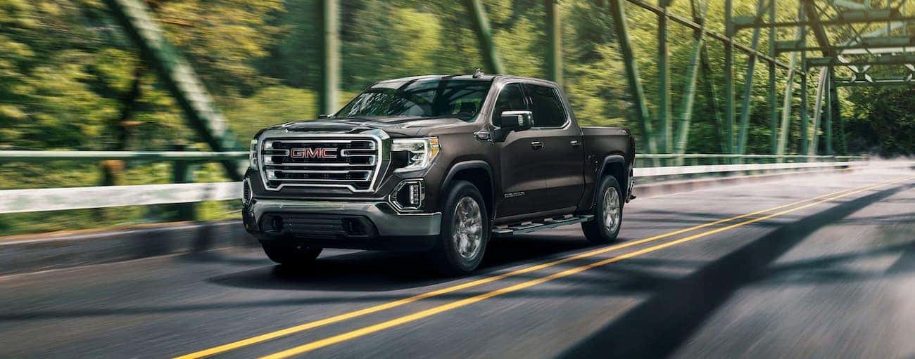 A grey 2020 GMC Sierra 1500 SLT is driving over a bridge.