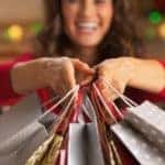 A woman is smiling while holding bags from Christmas shopping in Atlanta, GA.
