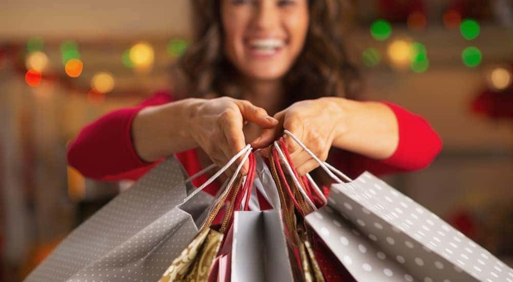 A woman is smiling while holding bags from Christmas shopping in Atlanta, GA.
