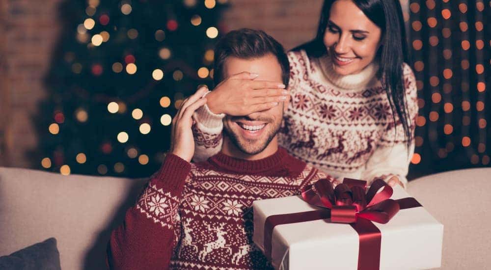 A woman is surprising her boyfriend with a gift for Christmas.