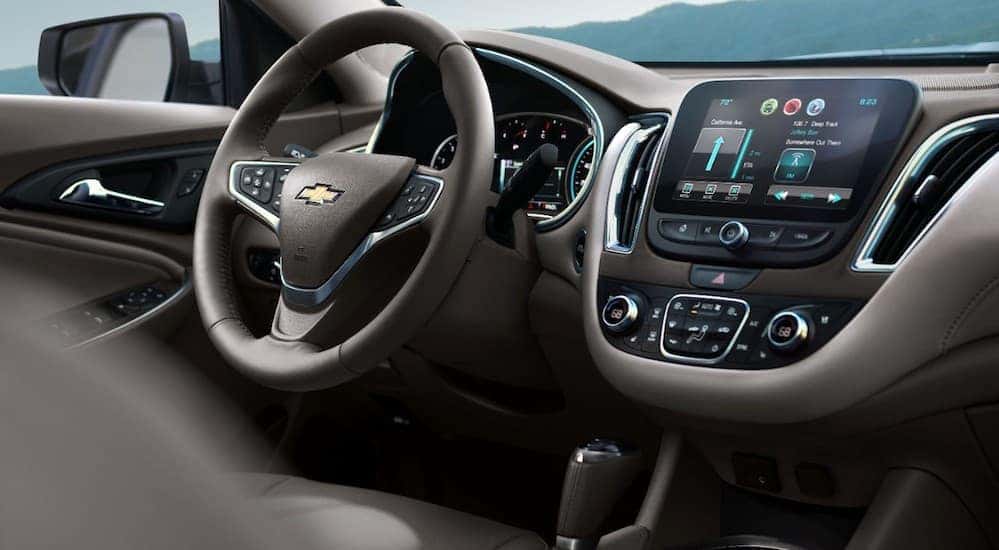 The front interior of a 2016 Chevy Malibu is shown with an infotainment system.