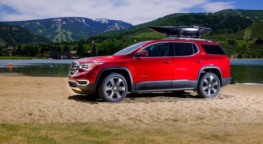 A red 2018 GMC Acadia, a popular option among used cars for sale in Atlanta, GA, is parked on sand next to a lake.