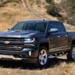 A black 2018 Chevy Silverado 1500, a popular option among the used trucks for sale in Atlanta, GA, is parked in a grassy field.
