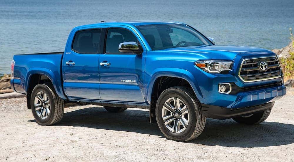 A blue 2016 Toyota Tacoma is parked next to a beach.