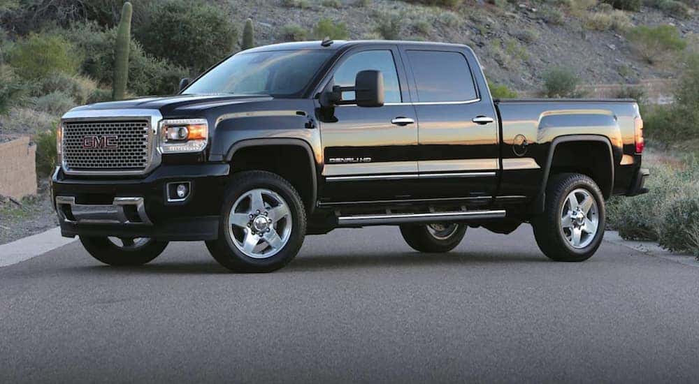 A black 2020 GMC Sierra HD is parked next to a dirt hill at dusk.