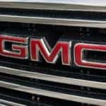 A close up of a GMC truck grille is shown with red "GMC" lettering.