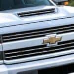 A close up of the golden Chevy logo is shown on a white Chevy Silverado truck.