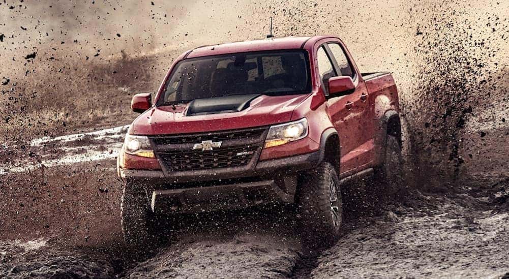A red 2020 Chevy Colorado is off-roading through a mud pit.