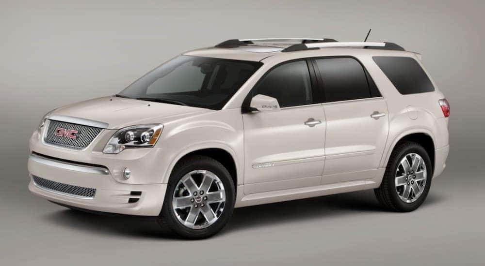 A white 2011 GMC Acadia Denali, which is popular among used SUVs for sale, is on a grey background.