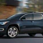A blue 2019 GMC Acadia is driving past a blurred background near Albany, NY.