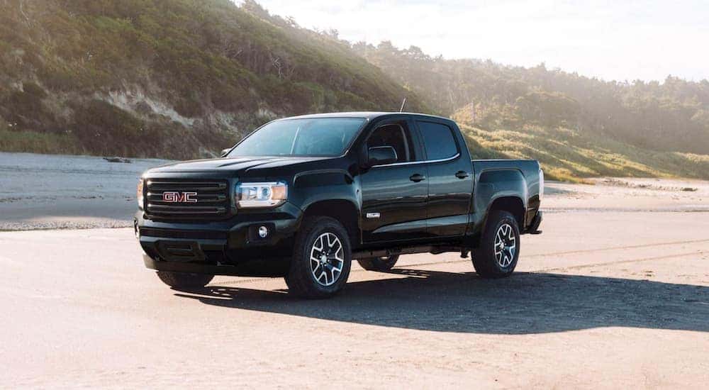 A black 2020 GMC Canyon is parked on beach sand.