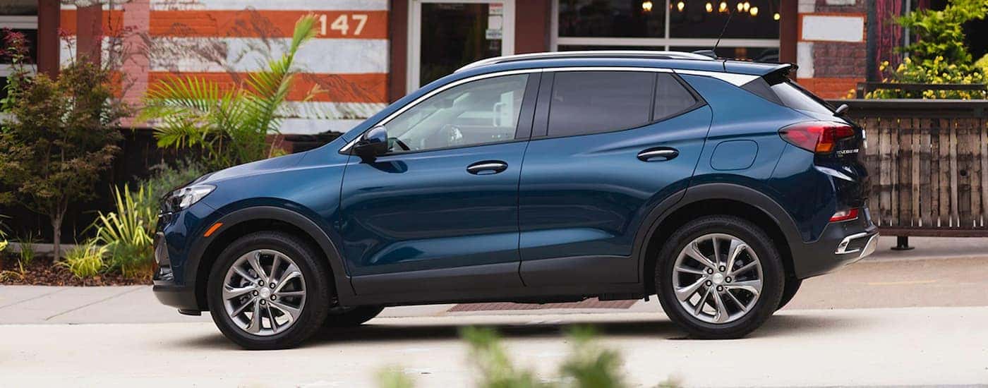 A blue 2020 Buick Encore GX is shown from the side in front an orange and white building.